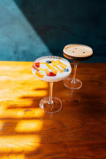 Leckerer Cocktail mit beim Amami Restaurant in Kiel auf gut beleuchtetem Holztisch vor türkisem Hintergrund